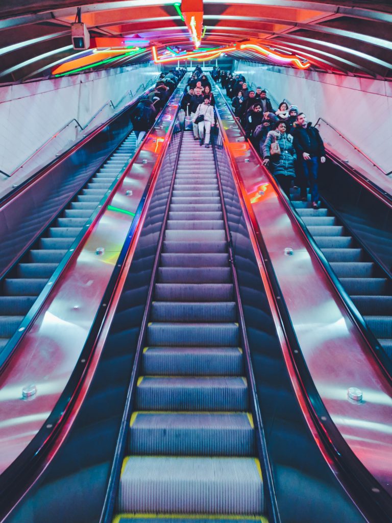 a red escalator with people on the stairs