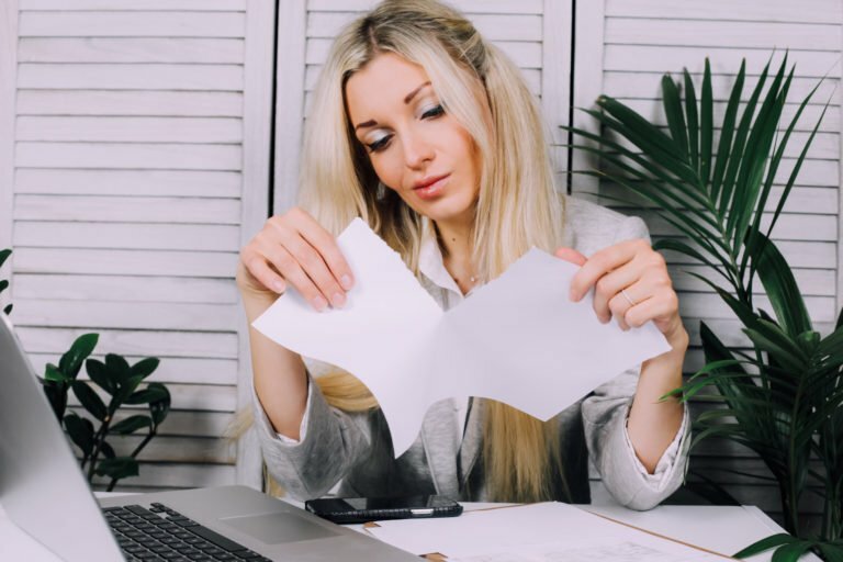 Young business woman ripping up a contract document sitting on a desk at the office